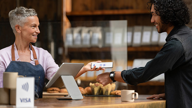 Small business purchase made with watch and phone with Visa logo displayed.
