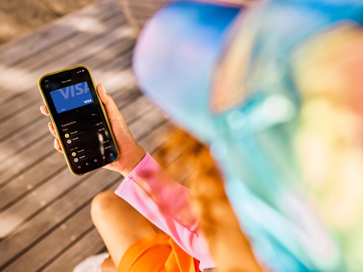 Person looking at phone with image of Visa-branded card on it.