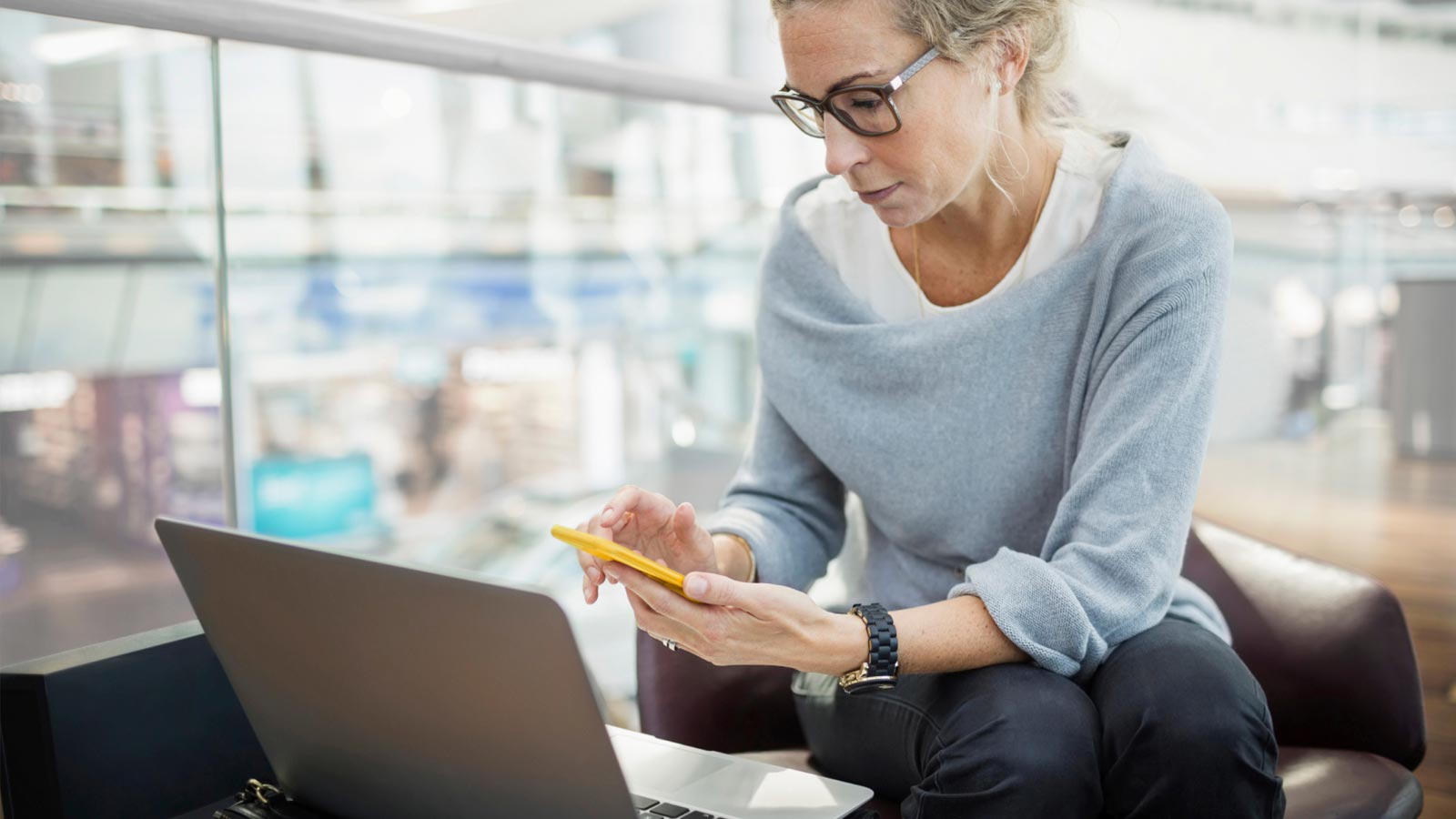 female sitting with laptop and phone