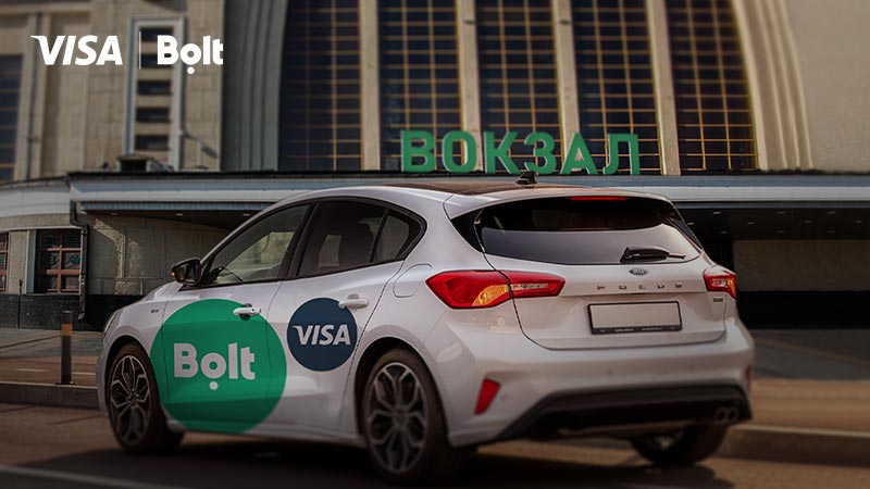 A Bolt taxi car with logos of Visa and Bolt near the railway station