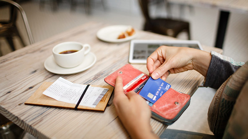 Woman removing credit card from her wallet to pay for meal.